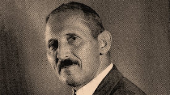 Eduard Reichenow Leicht seitliches Schwarz-weiß-Foto von Eduard Reichenow mit verschränkten Armen und Zigarillo in der rechten Hand