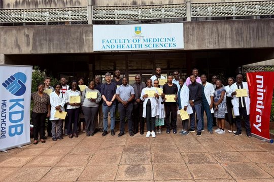Trainers and participants at POCUS course The picture shows a big group of people standing in front of a hospital. Some people have certificates in their hands.