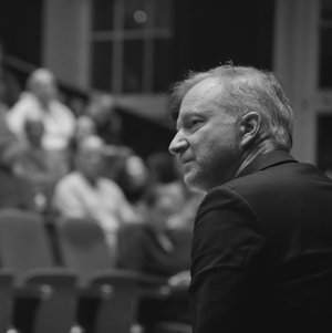 Black and white photo of Thomas Großbölting from the side, in the background the fully occupied lecture hall of the BNITM