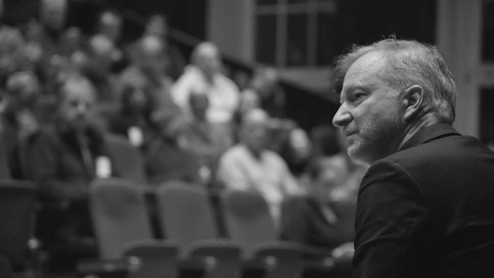 Schwarz-Weiß-Foto von Thomas Großbölting von der Seite, im Hintergrund der voll besetzte Hörsaal des BNITM