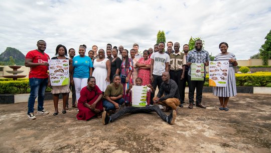 Training participants and lecturers of the training held on 7th of March 2024 Das Bild zeigt eine Gruppe von Menschen, die draußen Plakate mit Schlangen hochhalten.