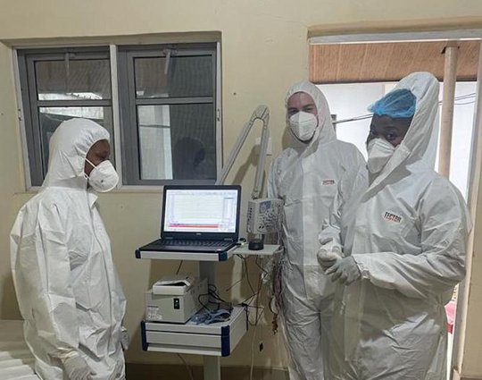 Three researchers in protective suits in a patient room. EEG team at ISTH.