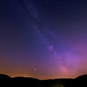 Lichtverschmutzung Das Foto zeigt einen städtischen Nachthimmel mit starker Lichtverschmutzung über den umgebenden Bergen.