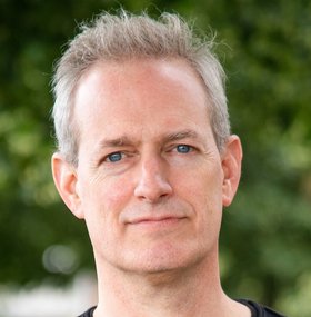 Dr. Tobias Spielmann Dr. Tobias Spielmann: ein Forscher mit kurzen, grauen Haaren und einem Dreitagebart, der ein dunkles Oberteil trägt.