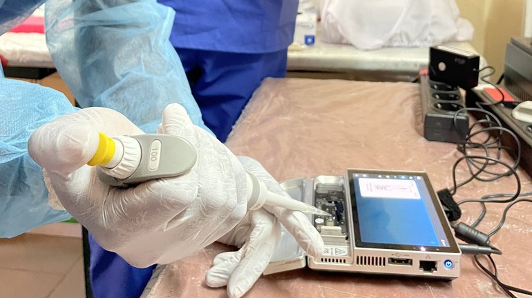 Loading of a sequencing device A scientific staff wearing personal protective gear using a pipette to load a sample into a sequencing device.