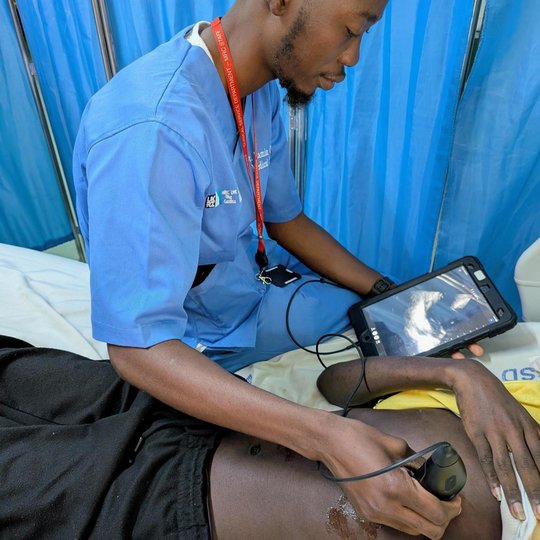 CLASH Study The picture shows a man scanning a patient with an ultrasound probe. At the same time he is looking at the ultrasound on a tablet.