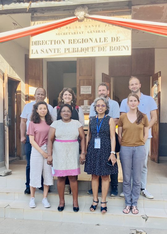 CoBoGo Zu sehen ist eine kleine Gruppe von Forscher:innen des CoBoGo Teams, das vor einem Hauseingang steht und in die Kamera lacht.