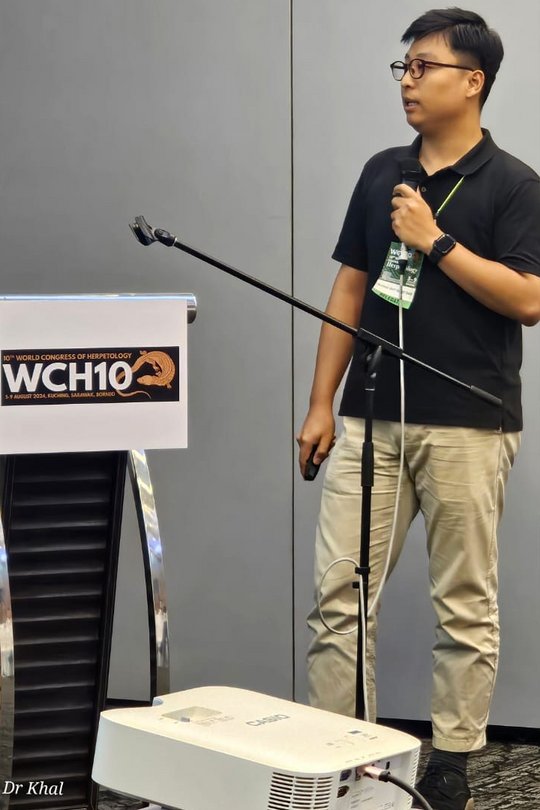 Truong Quy Quoc Bao at the 10th World Congress of Herpetology The picture shows a man standing holding a microphone.
