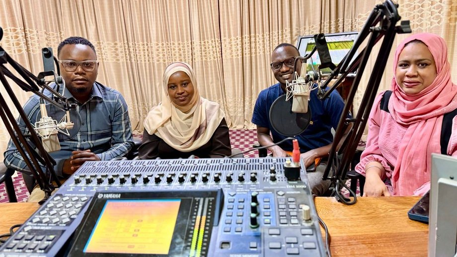 4 people in a radio station in front of a microphone