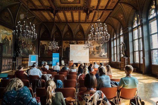 Eröffnungszeremonie der Behavioral Insights Summer School (BISS) 2018 Eine Gruppe von Menschen sitzt auf Stühlen in einem geschmückten Raum.