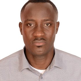 Bamidele Olorunsola, a researcher in a grey shirt and with short hair, directly at the camera, exuding professionalism and focus.