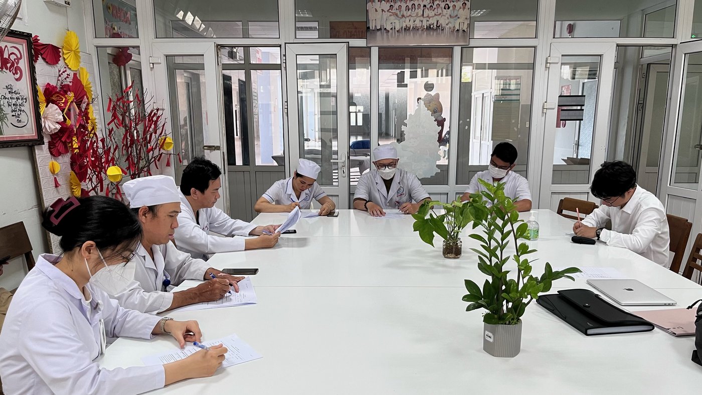Healthcare workers in Ninh Thuan Hospital answering a survey on knowledge and practice in snakebite management. The picture shows several people in white scrubs sitting around a table filling out a paper questionnaire.