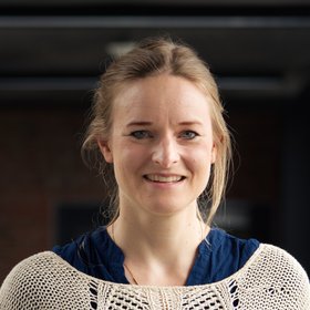 Dr Christine Hopp: a researcher with blond hair tied back, dark blue blouse and white and beige mesh sweater.