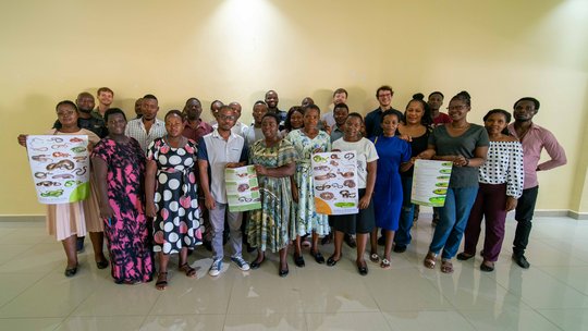Training participants and lecturers of the training held on the 8th of March 2024 Das Bild zeigt eine Gruppe von Menschen, die Poster mit Schlangen hochhalten.