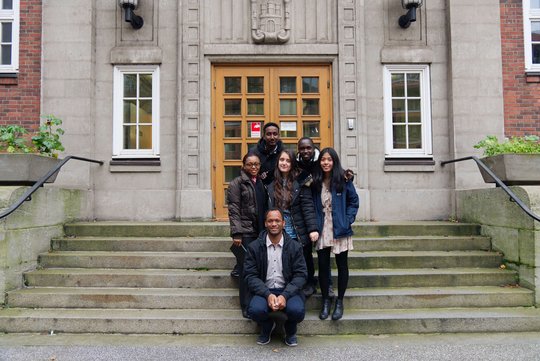 OMTG Grant holders from 2019. Eine Gruppe von 6 jungen Forschern, die als fröhliche Gruppe auf einer steinernden Treppe vor einem Antiken Gebäude stehen.