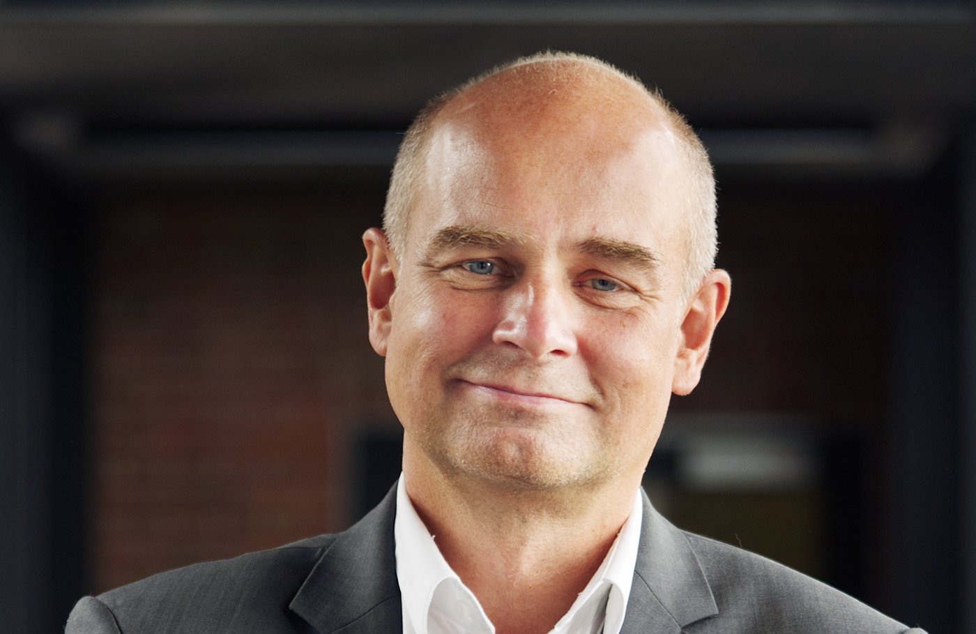 Prof. Dr. Jürgen May Prof. Dr. Jürgen May:ein Forscher, der eine Glatze hat und ein weißes Hemd mit grauem Sakko trägt.