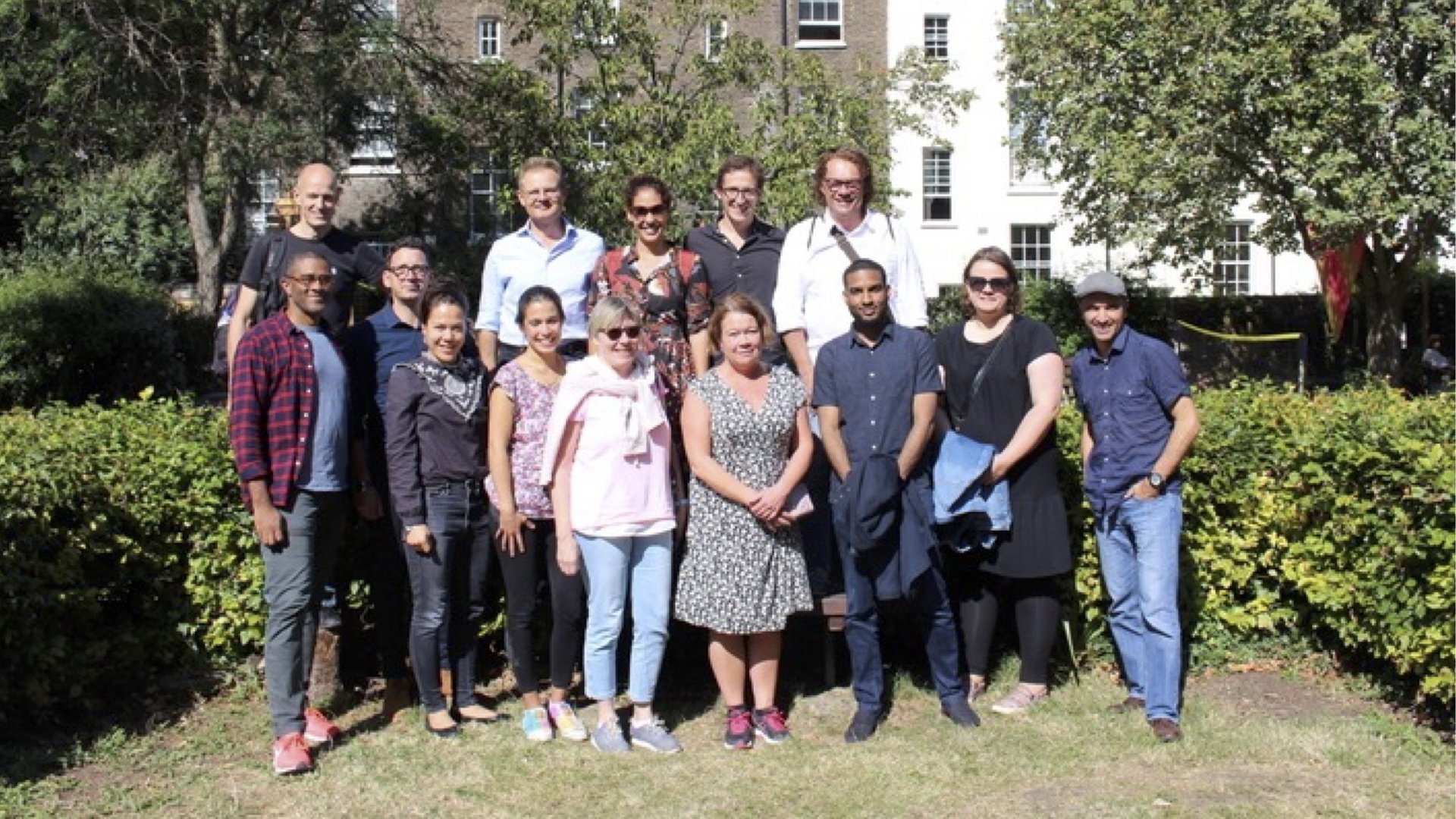 Die internationalen Mitglieder des tropEd-Netzwerks für "Education in International Health" stehen lächelnd in einem Garten.