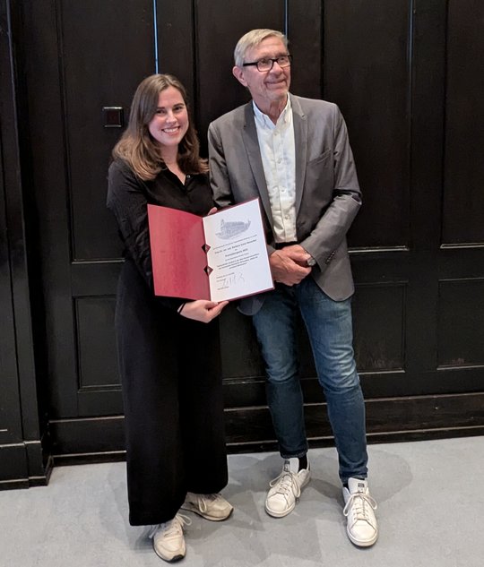 Dr Barbara Honecker receives her doctoral award from the BNITM Friends Association A board member of the Association of Friends of the Tropical Institute presents Barbara Honecker with a certificate at the award ceremony in the lecture theatre of the Bernhard Nocht Institute. In the background you can see a wall panelled in dark brown