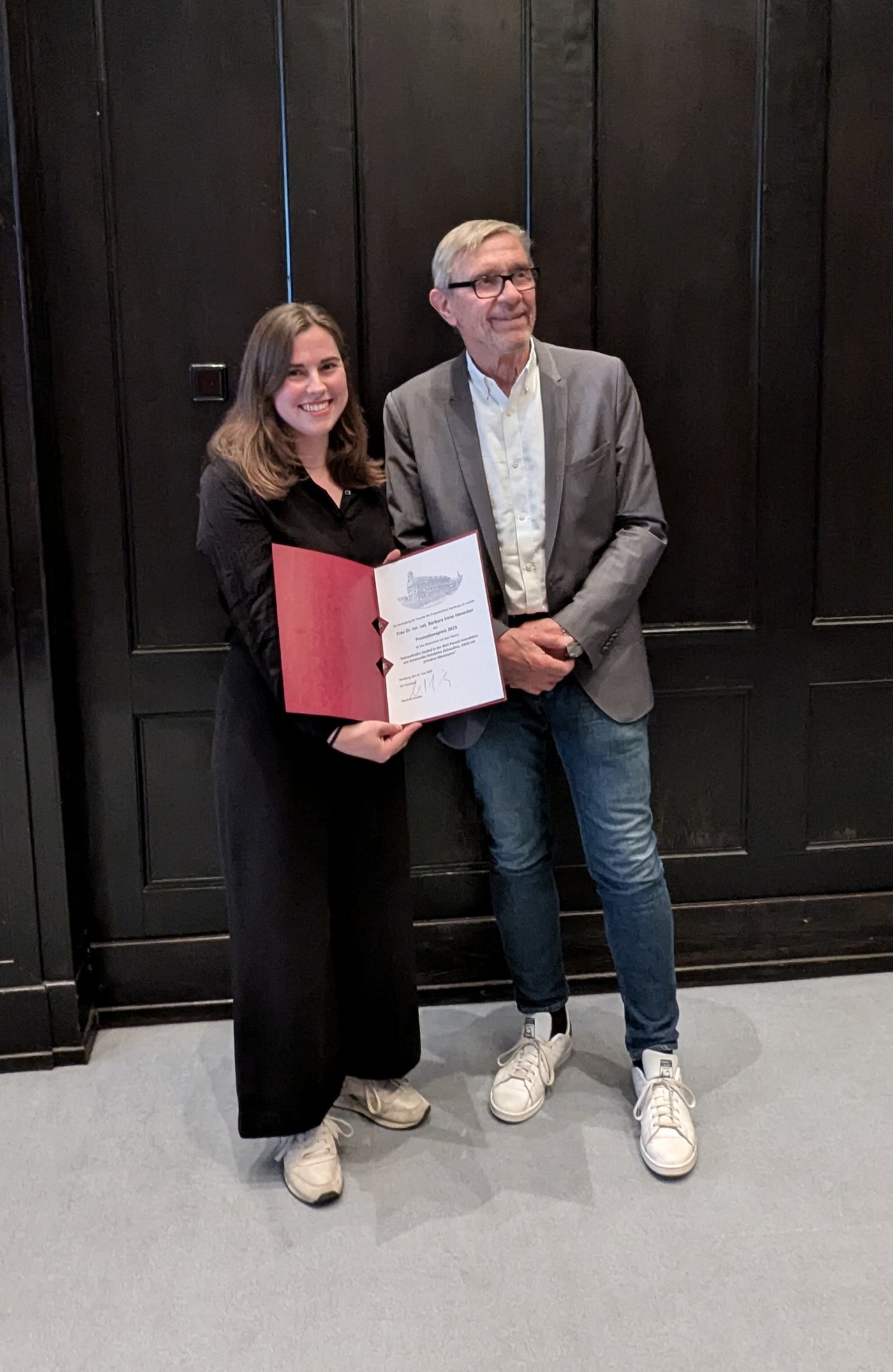 Dr Barbara Honecker receives her doctoral award from the BNITM Friends Association A board member of the Association of Friends of the Tropical Institute presents Barbara Honecker with a certificate at the award ceremony in the lecture theatre of the Bernhard Nocht Institute. In the background you can see a wall panelled in dark brown