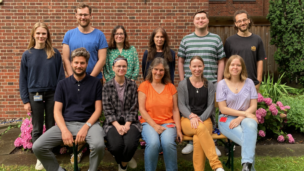 Freundliches, frontales Gruppenfoto im Grünen.