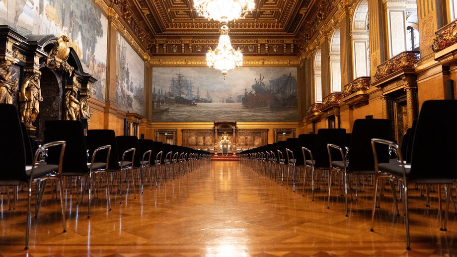 Großer Festsaal Foto vom Großen Festsaal des Hamburger Rathauses mit zwei Kronleuchtern an der Decke, edlem Parkett, reicher Bestuhlung links und rechts und historischen Wandgemälden.