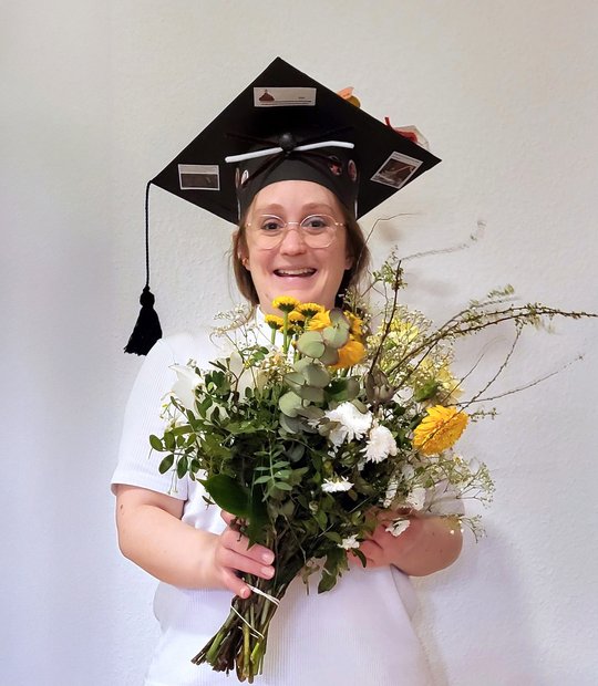 Annika Bea The picture shows Annika Bea after her disputation with a bouquet of flowers. She is also wearing a doctor's hat