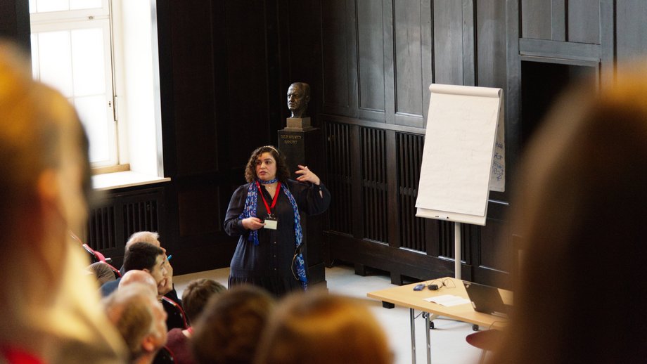 LCI-Symposium Motivierte Forscherin, die einen Vortrag in einem gefüllten Hörsaal hält.