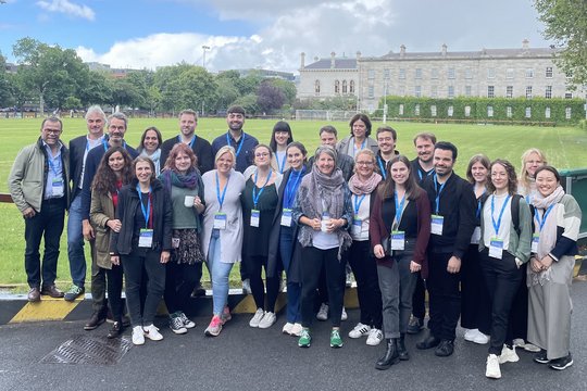 Members of the Sex Differences in Immunity research group FOR 5068 in front of the Trinity College Dublin Members of the Sex Differences in Immunity research group stand outside a grassy area and Trinity College in Dublin. They all look cheerful and wear a conference badge around their necks