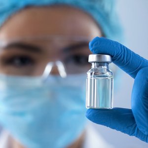 SCIENCE: Kommunikation der US-Gesundheitsbehörde CDC unterminiert Vertrauen in Impfungen Foto einer Person mit Mund-Nasenschutz und blauen Laborhandschuhen und einer Impfampulle in der Hand
