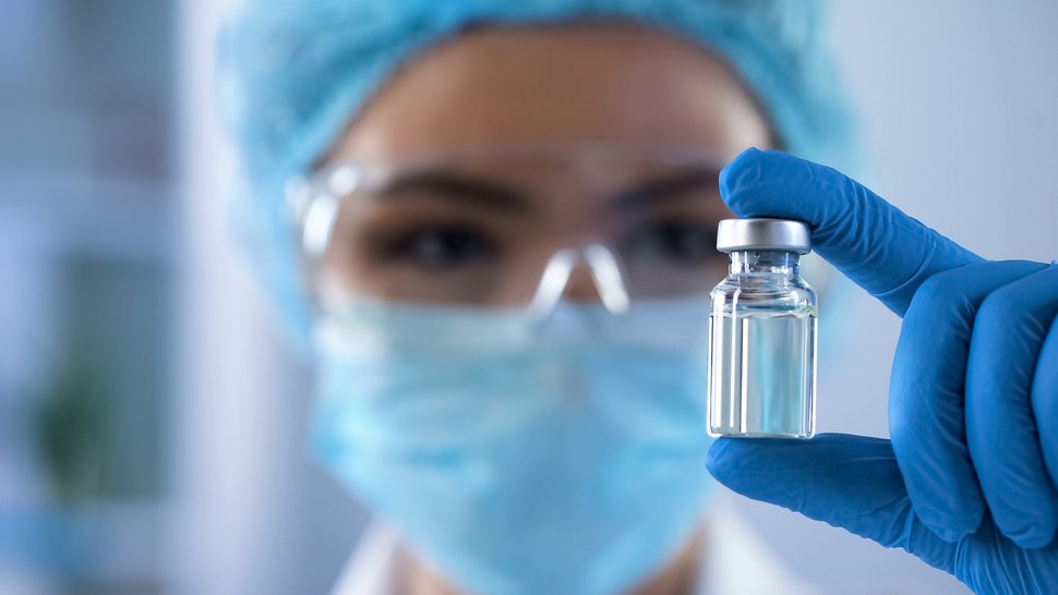SCIENCE: Kommunikation der US-Gesundheitsbehörde CDC unterminiert Vertrauen in Impfungen Foto einer Person mit Mund-Nasenschutz und blauen Laborhandschuhen und einer Impfampulle in der Hand