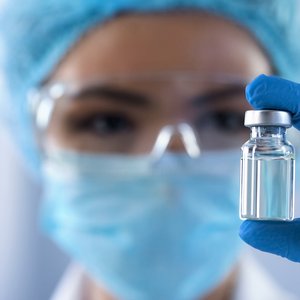 SCIENCE: Communication from the US Centers for Disease Control and Prevention (CDC) undermines trust in vaccinations A photo of a person wearing a face mask and blue laboratory gloves, holding a vial of vaccine