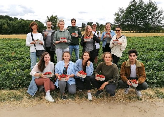 Company excursion Aumühle/Börnsen July 2022. Betriebsausflug der AG Molekulare Infektionsimmunologie: eine Gruppe steht vor einem Erdbeerfeld und halten jeweils eine Schale Erdbeeren in die Kamera.