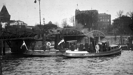 The black-and-white photo shows the harbour doctor standing on a barge with other men in uniform, on their way to the ship's crew.