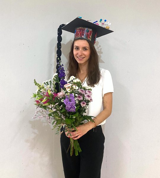 Melanie Lütkemeyer Melanie Lütkemeyer stands in front of a wall in the foyer of the Institute of Plant Sciences and Microbiology after her defence. She proudly wears her doctoral hat and carries a colourful bouquet of flowers