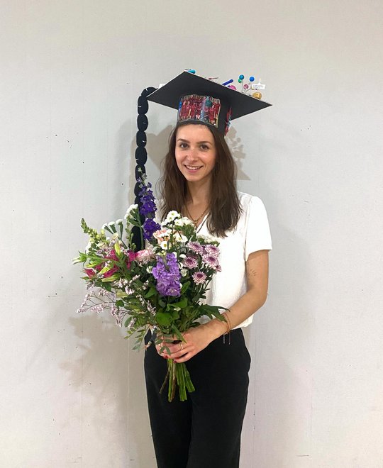 Melanie Lütkemeyer Melanie Lütkemeyer stands in front of a wall in the foyer of the Institute of Plant Sciences and Microbiology after her defence. She proudly wears her doctoral hat and carries a colourful bouquet of flowers