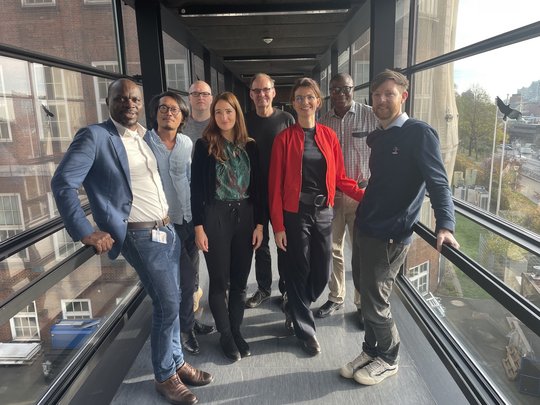 Die Gruppenleitungen der Sektion Implementationsforschung. Die Gruppenleitungen der Sektion Implementationsforschung stehen in einem gläsernden Durchgang und lächeln in die Kamera.