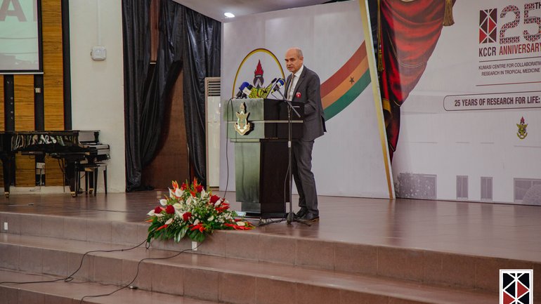 The Chairman of the Board of the BNITM, Prof. Jürgen May The Chairman of the Board of the BNITM, Prof. Jürgen May, stands at the lectern adorned with flowers and gives his speech.