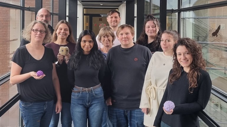 AG Mücken-Virus-Interaktion AG Mücken-Virus-Interaktion: Die Gruppe steht in einem gläsernden Übergang und schaut in die Kamera.