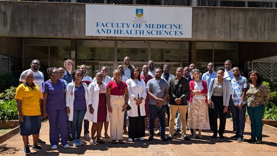 Group picture of the participants and trainers of the POCUS training at the University of Zimbabwe The picture shows a group of people standing in front of a sign saying "Faculty of Medicine and Health Sciences"