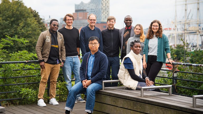 Team photo of the Research Group Neglected Diseases and Envenoming The picture shows a group of nine people. Two are sitting on a bench in the foreground. In the background the other seven stand.