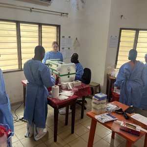 Laboratory Training for Diagnostic of Viral hemorrhgagic fever viruses at CIPEC-BA, Parakou, Benin Photo of several international scientists in a room with louvred windows. Two colleagues are working on the glove box.