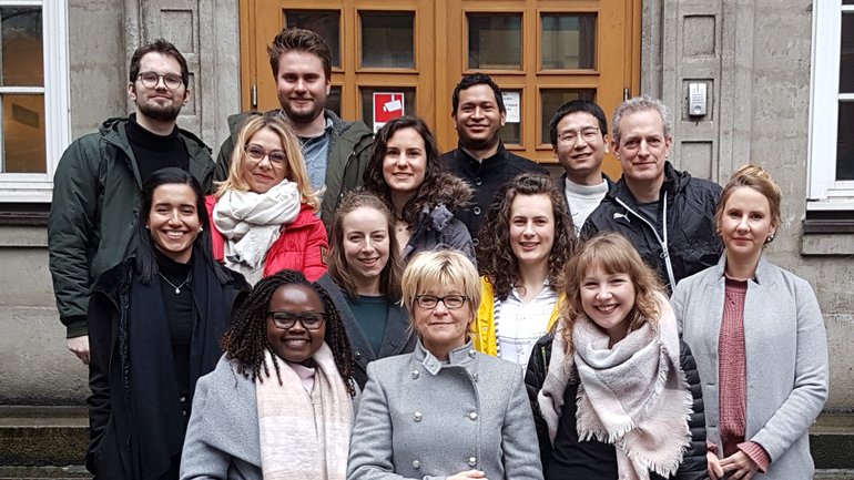 AG Spielmann AG Spielmann: Eine Gruppe steht draußenauf einer Treppe. Alle tragen warme Winterkleidung und stehen auf einer Treppe vor einem Eingang.