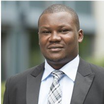 Alex Olengo, a man in formal attire, including a suit and tie, is depicted as a researcher, exuding professionalism and intellect.