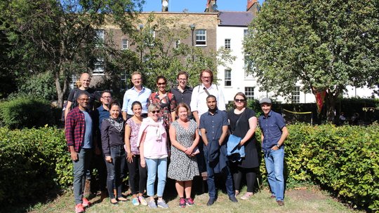 Member institute of tropEd Network for Education in International Health Die internationalen Mitglieder des tropEd-Netzwerks für "Education in International Health" stehen lächelnd in einem Garten.