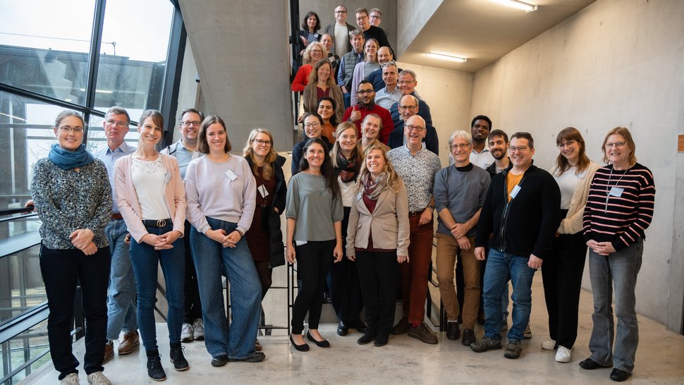 Die Teilnehmenden der Vollversammlung des Leibniz-Forschungsverbunds INFECTIONS stehen für ein Gruppenfoto im Treppenhaus beisammen.