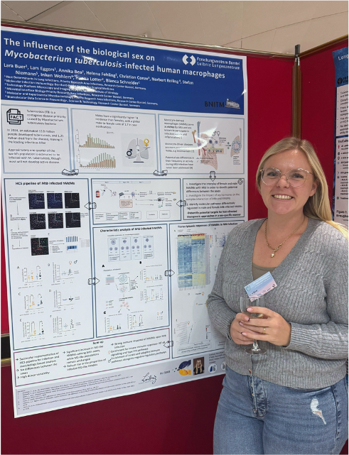 Lara Buer presenting her poster Lara Buer stands to the right of her poster and smiles warmly at the camera. She is wearing jeans and a gray pullover.